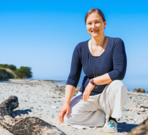 Frau hockt im Sand am Meer - über mich